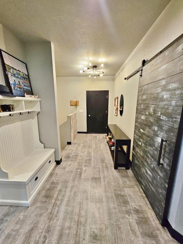 1007 5th St, Rugby, ND 58368 - mudroom with a barn door, light wood finished floors, a textured ceiling, and a chandelier