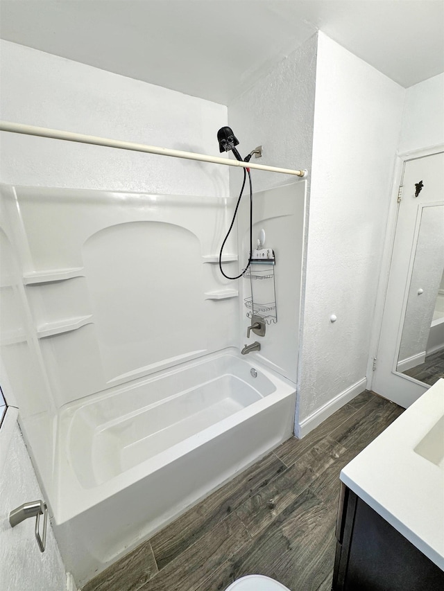 1201 Soo St, Minot, ND 58701 - bathroom with wood finished floors, baseboards, shower / bath combination, a textured wall, and vanity