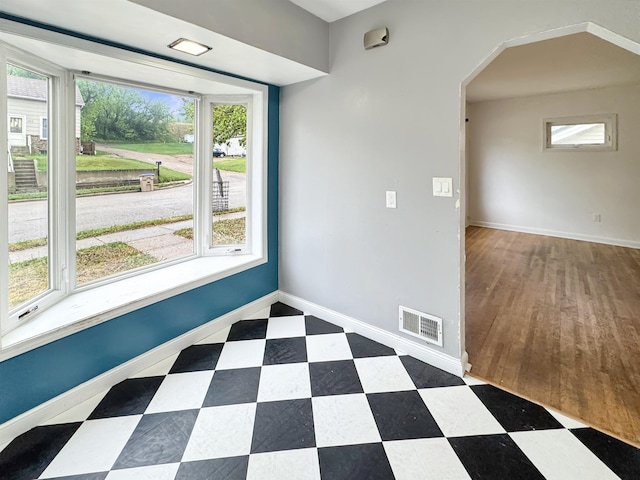 1201 Soo St, Minot, ND 58701 - empty room featuring arched walkways, tile patterned floors, and baseboards