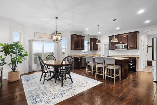 1804 Valley Bluffs Dr, Minot, ND 58701 - dining area featuring arched walkways, recessed lighting, dark wood-style flooring, and baseboards