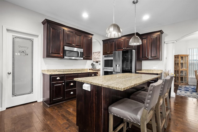 1804 Valley Bluffs Dr, Minot, ND 58701 - kitchen with arched walkways, stainless steel appliances, dark wood-type flooring, hanging light fixtures, and recessed lighting