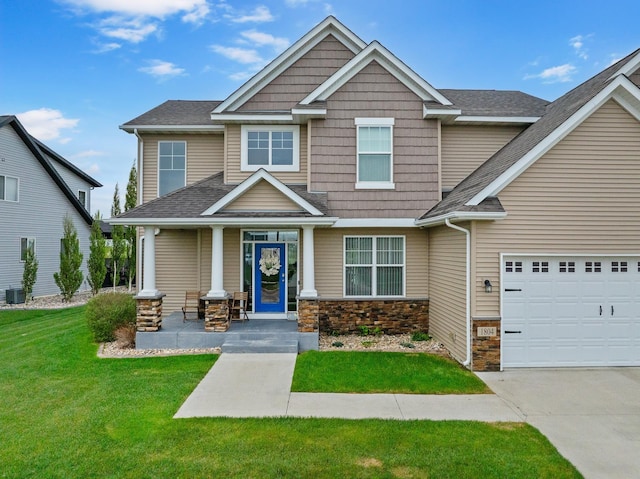 1804 Valley Bluffs Dr, Minot, ND 58701 - craftsman inspired home with covered porch, stone siding, a front yard, a garage, and concrete driveway