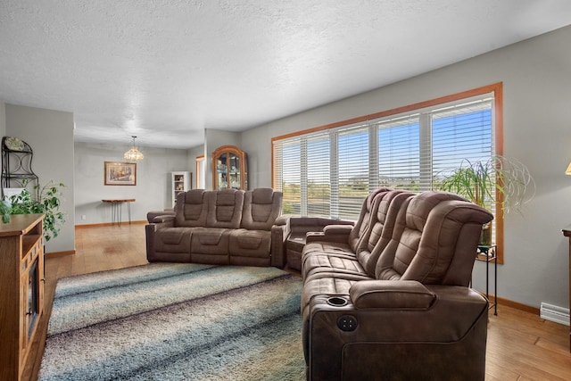3900 16th St, Minot, ND 58703 - living room featuring a chandelier, baseboards, light wood-style flooring, and a textured ceiling