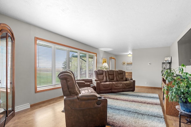 3900 16th St, Minot, ND 58703 - living room with wood finished floors, baseboards, a textured ceiling, and a baseboard radiator