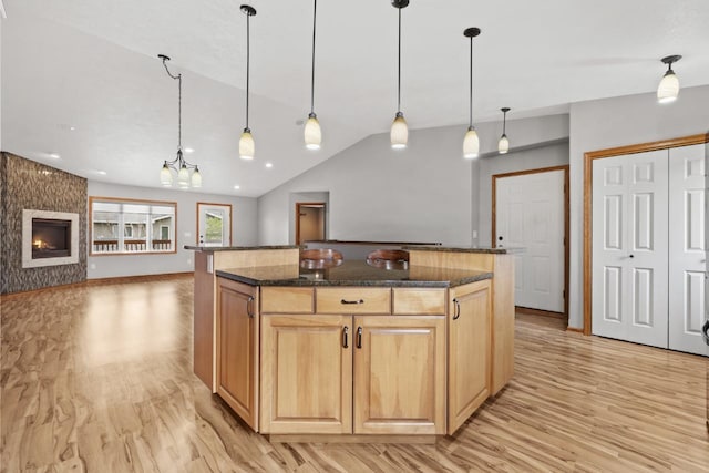 625 34th Ave Unit A, Minot, ND 58701 - kitchen with light wood finished floors, a kitchen island, dark stone countertops, open floor plan, and vaulted ceiling