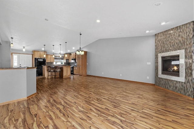 625 34th Ave Unit A, Minot, ND 58701 - kitchen featuring light wood-style flooring, open floor plan, black appliances, a breakfast bar area, and dark countertops