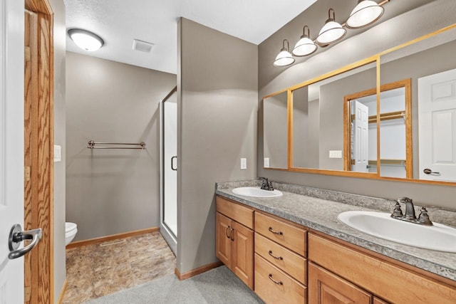 625 34th Ave Unit A, Minot, ND 58701 - bathroom featuring a shower stall, toilet, double vanity, and baseboards