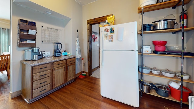 200 E 1st St, Velva, ND 58790 - kitchen featuring freestanding refrigerator, wood finished floors, and brown cabinetry