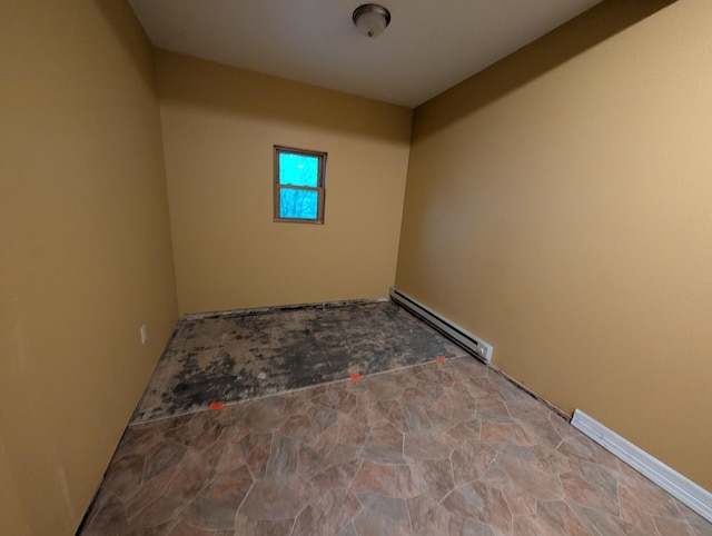 807 NW 8th St, Minot, ND 58703 - spare room featuring a baseboard heating unit and stone finish flooring