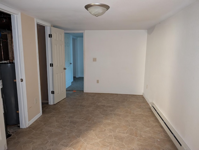 807 NW 8th St, Minot, ND 58703 - empty room with baseboard heating, water heater, baseboards, and stone finish floors