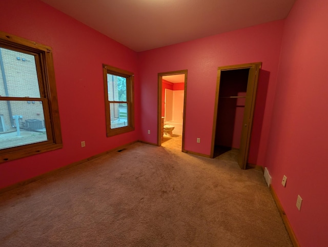 807 NW 8th St, Minot, ND 58703 - unfurnished bedroom featuring light colored carpet, ensuite bath, a closet, baseboards, and a spacious closet
