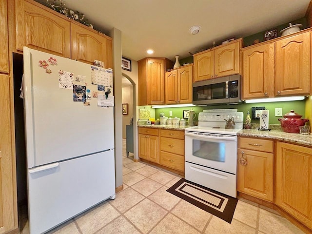 2900 8th St, Minot, ND 58701 - kitchen with white appliances, recessed lighting, arched walkways, light tile patterned floors, and light stone counters