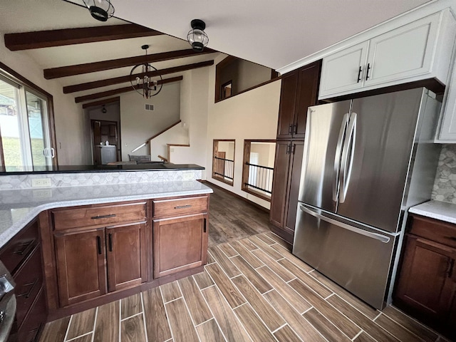 1003 NW Harrison Dr, Minot, ND 58703 - kitchen with freestanding refrigerator, dark wood-type flooring, hanging light fixtures, white cabinetry, and a chandelier