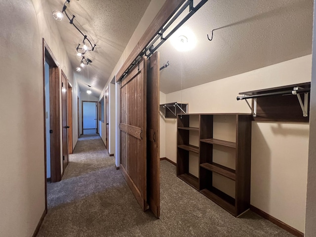 1003 NW Harrison Dr, Minot, ND 58703 - hallway with a barn door, a textured ceiling, dark carpet, and baseboards