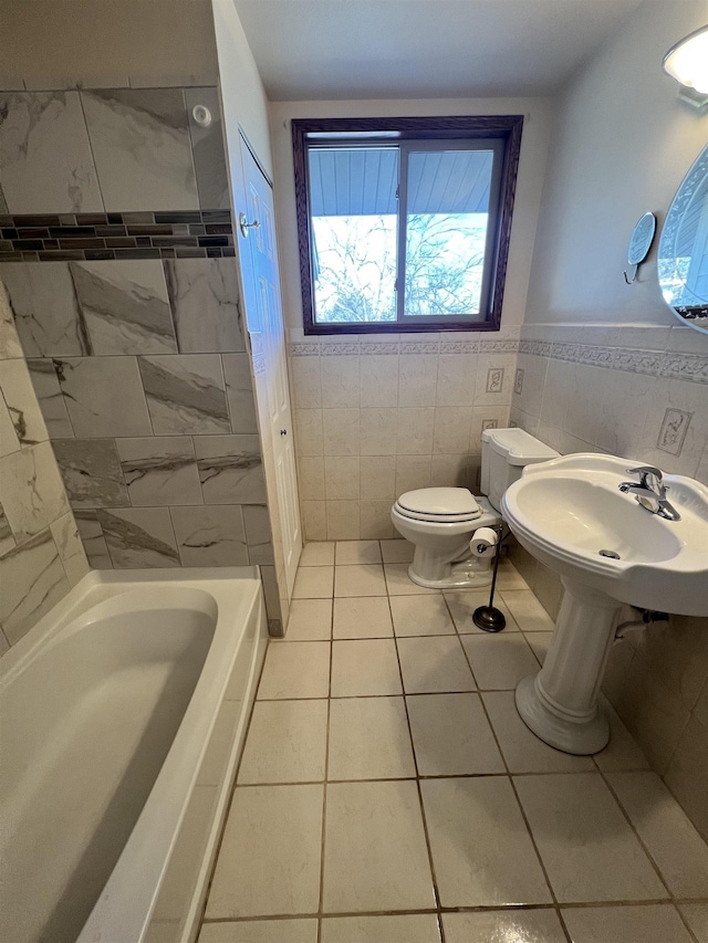 1003 NW Harrison Dr, Minot, ND 58703 - full bathroom with toilet, tile patterned flooring, tile walls, a sink, and a wainscoted wall