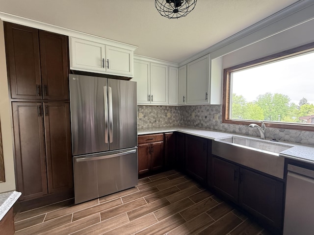 1003 NW Harrison Dr, Minot, ND 58703 - kitchen featuring appliances with stainless steel finishes, a sink, wood tiled floors, tasteful backsplash, and white cabinets