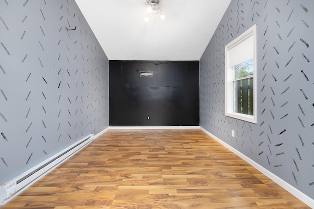 1111 15th St, Minot, ND 58703 - additional living space with a baseboard heating unit, light wood-style floors, and wallpapered walls
