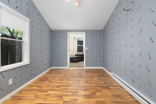 1111 15th St, Minot, ND 58703 - bonus room featuring a baseboard radiator, light wood-style floors, and vaulted ceiling