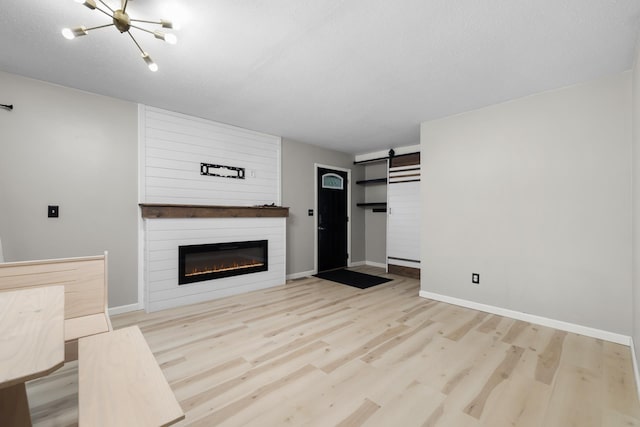 1111 15th St, Minot, ND 58703 - unfurnished living room featuring baseboards, wood finished floors, a chandelier, and a barn door