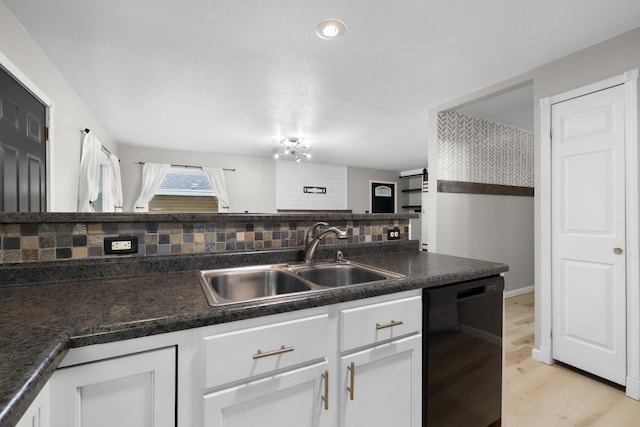1111 15th St, Minot, ND 58703 - kitchen featuring black dishwasher, a sink, decorative backsplash, and white cabinets