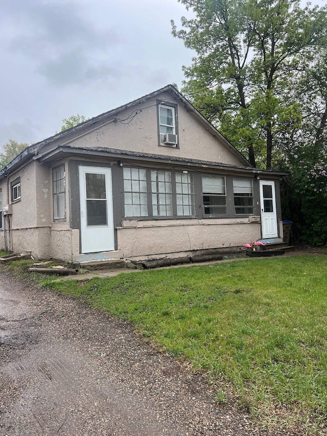 916 Valley St, Minot, ND 58701 - view of front of home featuring stucco siding, a front lawn, and cooling unit