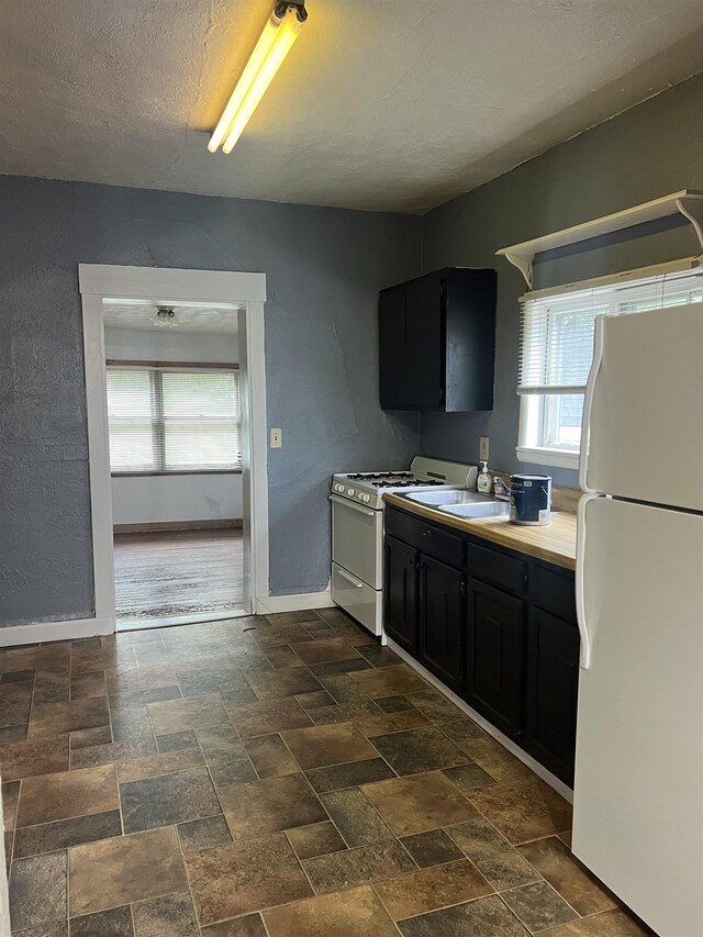 912 Valley St, Minot, ND 58701 - kitchen featuring white appliances, dark cabinets, dark stone finish flooring, baseboards, and light countertops