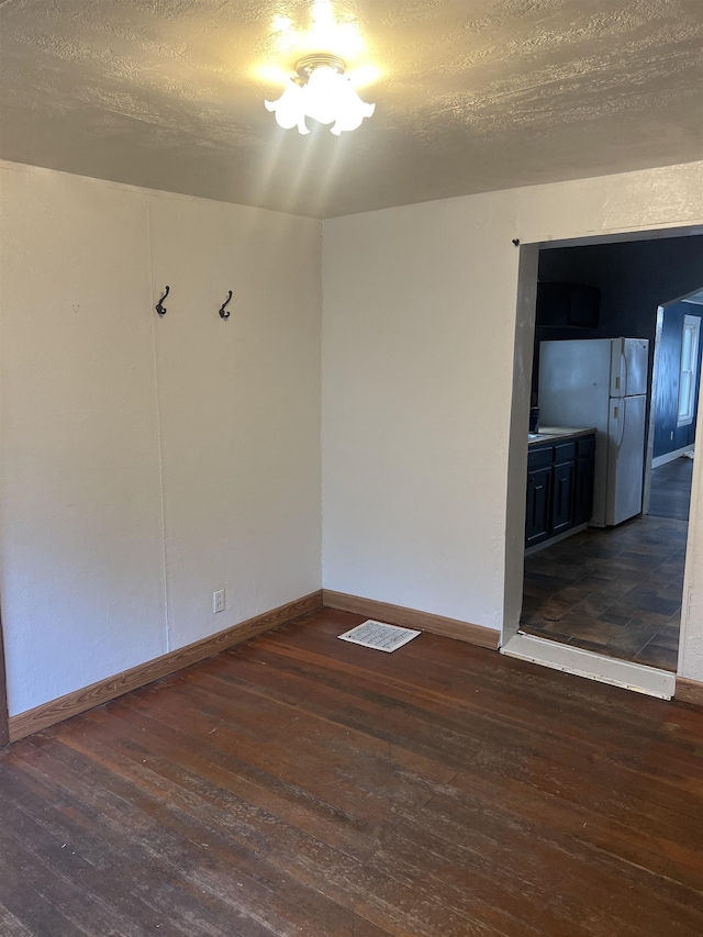 912 Valley St, Minot, ND 58701 - empty room featuring hardwood / wood-style floors, baseboards, and a textured ceiling