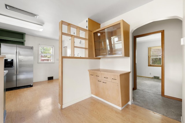 1200 9th St, Minot, ND 58703 - kitchen with stainless steel refrigerator with ice dispenser, light wood-style floors, light countertops, and arched walkways