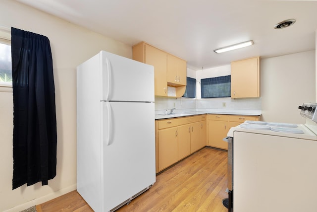 1200 9th St, Minot, ND 58703 - kitchen with white appliances, light wood-style floors, light countertops, backsplash, and cream cabinets