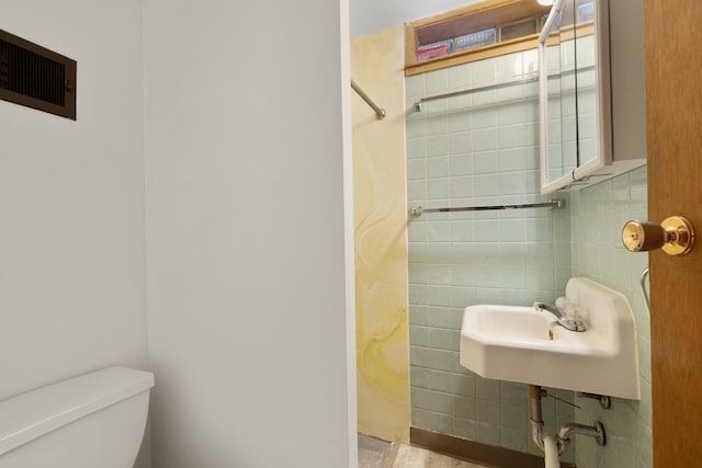 1200 9th St, Minot, ND 58703 - bathroom with toilet, a sink, and tile walls