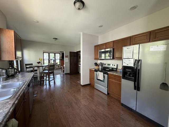 119 NW 6th St, Minot, ND 58703 - kitchen featuring appliances with stainless steel finishes, dark wood-type flooring, a sink, and dark countertops