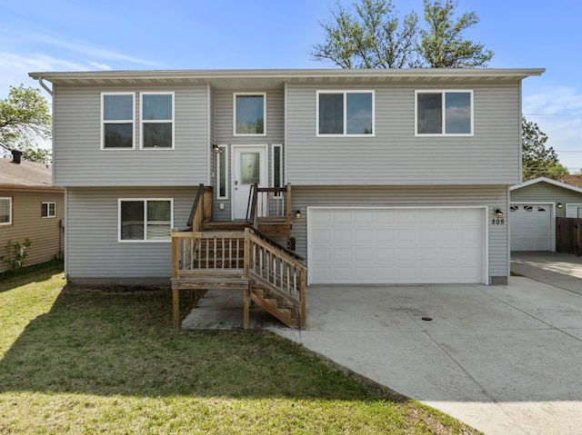 205 17th St, Minot, ND 58703 - raised ranch featuring a front yard, concrete driveway, and an attached garage