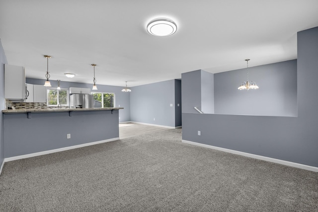 205 17th St, Minot, ND 58703 - unfurnished living room featuring a chandelier, light carpet, and baseboards