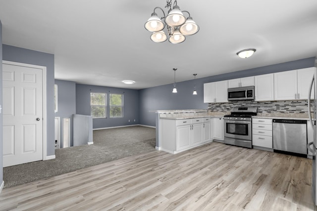 205 17th St, Minot, ND 58703 - kitchen with appliances with stainless steel finishes, a peninsula, light wood-type flooring, open floor plan, and white cabinets