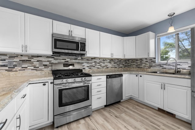 205 17th St, Minot, ND 58703 - kitchen with stainless steel appliances, a sink, white cabinetry, and tasteful backsplash
