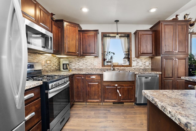 6351 53rd St, Plaza, ND 58771 - kitchen with appliances with stainless steel finishes, wood finished floors, a sink, backsplash, and light stone countertops
