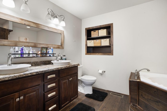6351 53rd St, Plaza, ND 58771 - bathroom featuring wood finished floors, double vanity, a bath, and toilet