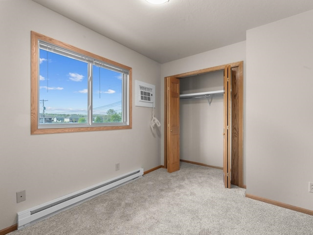 2301 2nd Ave Unit 2, Minot, ND 58701 - unfurnished bedroom with baseboard heating, light colored carpet, baseboards, a wall mounted AC, and a closet