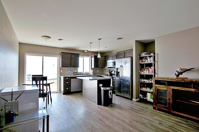 5304 15th Ave, Minot, ND 58701 - kitchen with stainless steel appliances, a center island, light wood-type flooring, dark brown cabinets, and decorative light fixtures
