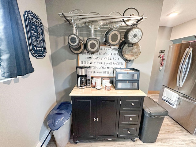101 6th St, Minot, ND 58703 - kitchen with light wood-type flooring, freestanding refrigerator, dark cabinets, baseboards, and light countertops