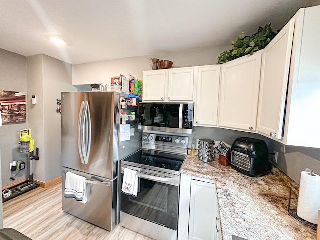101 6th St, Minot, ND 58703 - kitchen featuring appliances with stainless steel finishes, white cabinets, light wood-style floors, and light stone counters