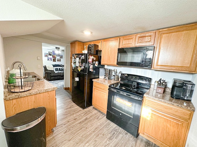 101 6th St, Minot, ND 58703 - kitchen with black appliances, light wood-style floors, light brown cabinets, a sink, and a textured ceiling