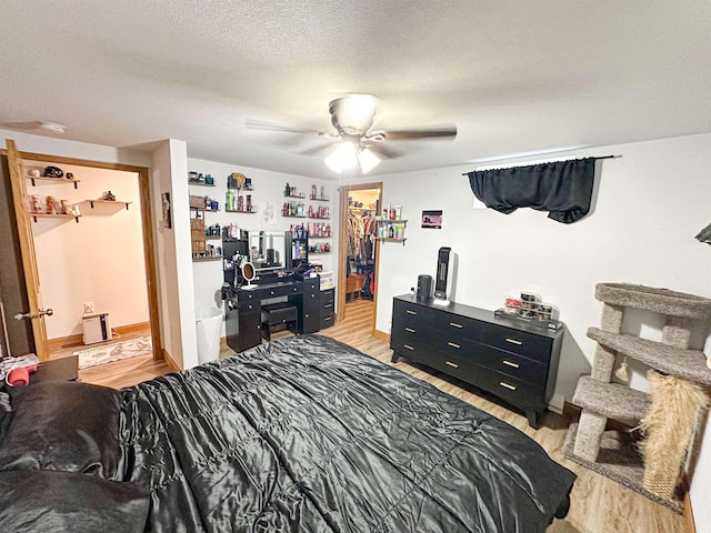 101 6th St, Minot, ND 58703 - bedroom featuring light wood-style floors, a ceiling fan, a spacious closet, a textured ceiling, and a closet