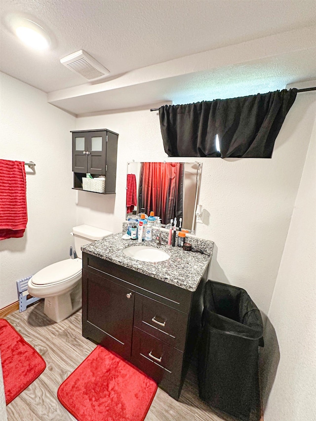 101 6th St, Minot, ND 58703 - bathroom featuring vanity, toilet, wood finished floors, and baseboards