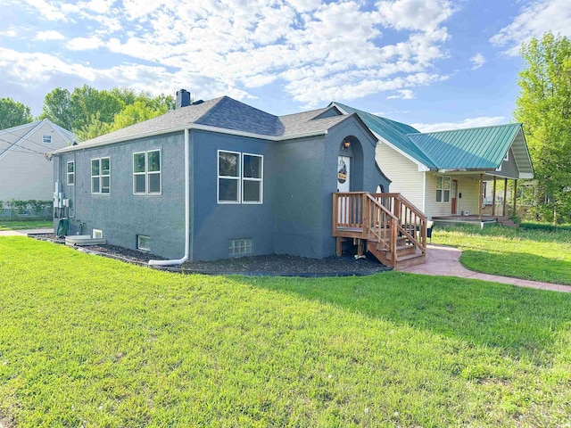 101 6th St, Minot, ND 58703 - view of side of property featuring a chimney, a yard, stucco siding, and roof with shingles