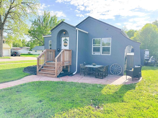 101 6th St, Minot, ND 58703 - back of property with a yard, stucco siding, and a patio
