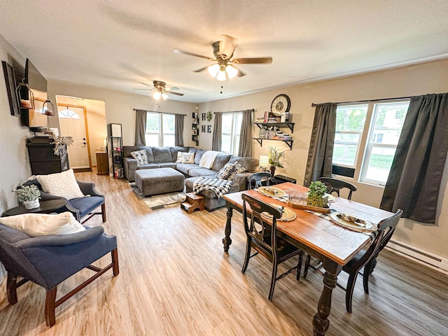 101 6th St, Minot, ND 58703 - dining room with light wood-style floors, baseboard heating, ceiling fan, baseboards, and a textured ceiling