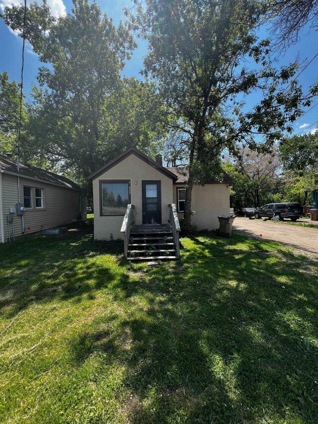 622 Central Ave, Minot, ND 58701 - back of house with stucco siding and a lawn