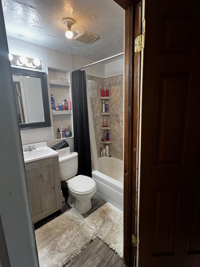 622 Central Ave, Minot, ND 58701 - full bathroom featuring toilet, vanity, shower / tub combo with curtain, wood finished floors, and a textured ceiling