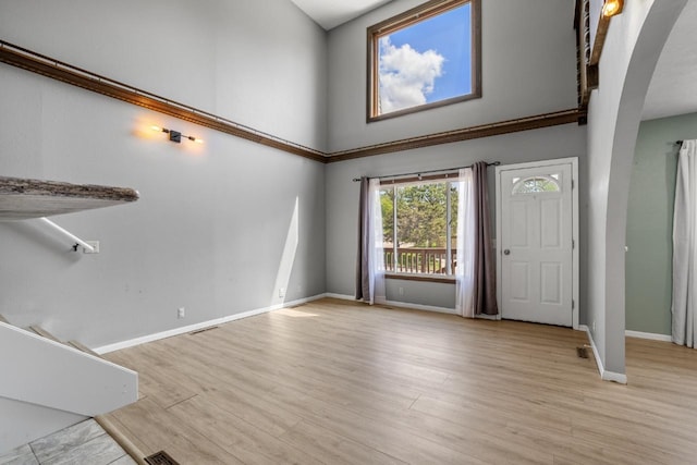 1127 8th St, Minot, ND 58703 - entryway featuring arched walkways, a towering ceiling, baseboards, and light wood finished floors